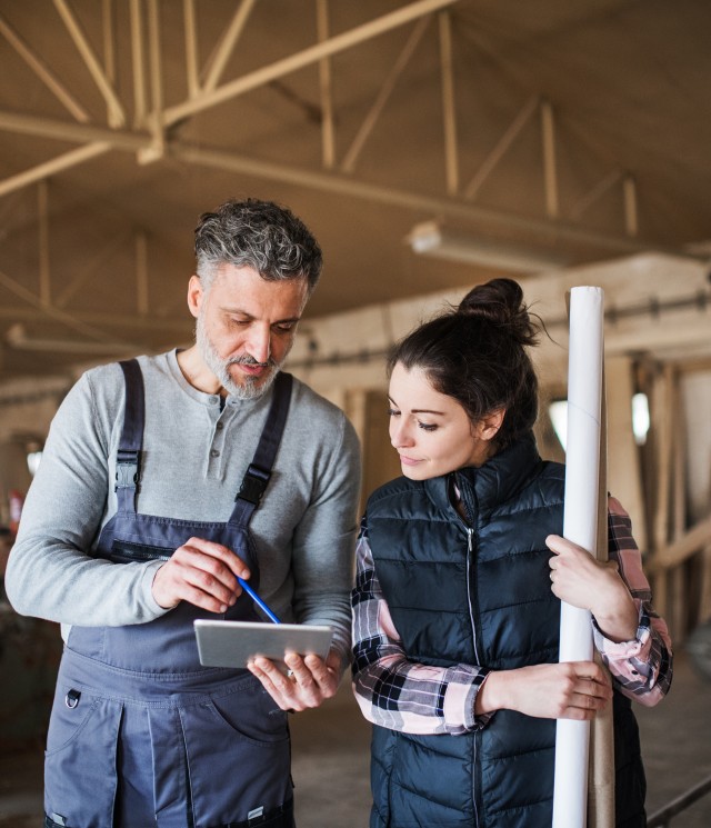 Homme et femme artisans du bâtiment regardant une tablette