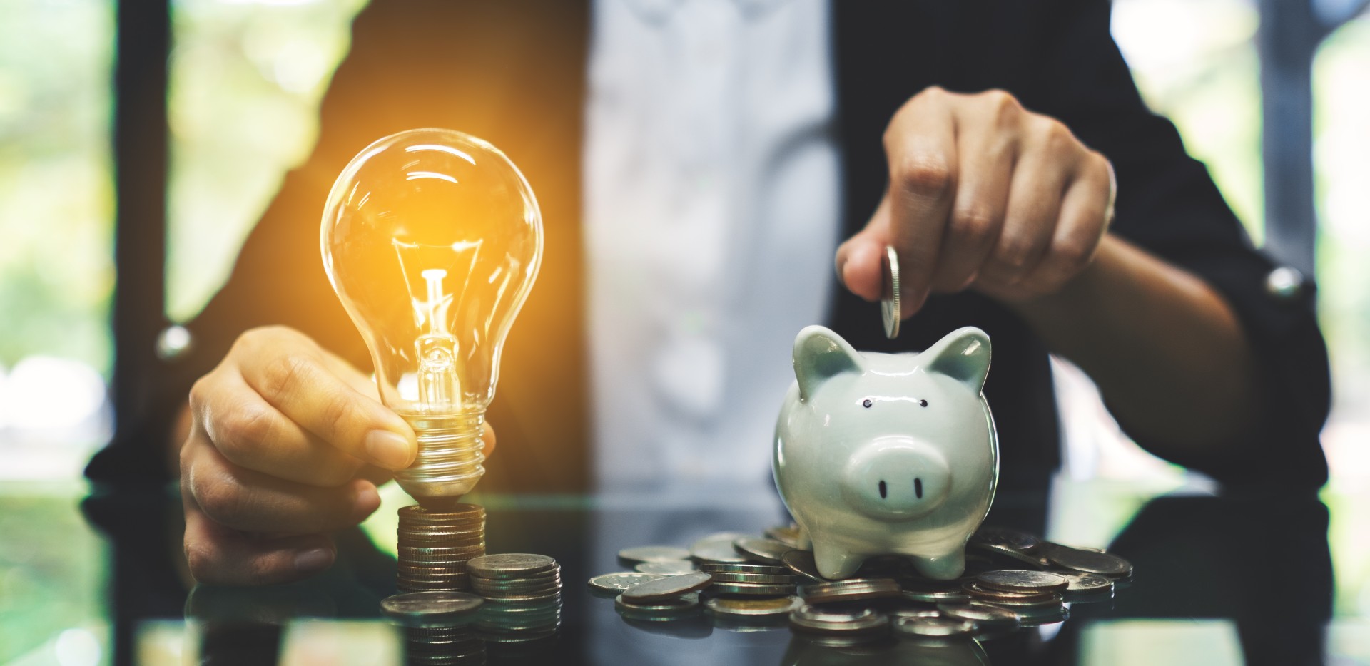 Homme tenant une ampoule et remplissant de pièces une tirelire en forme de cochon