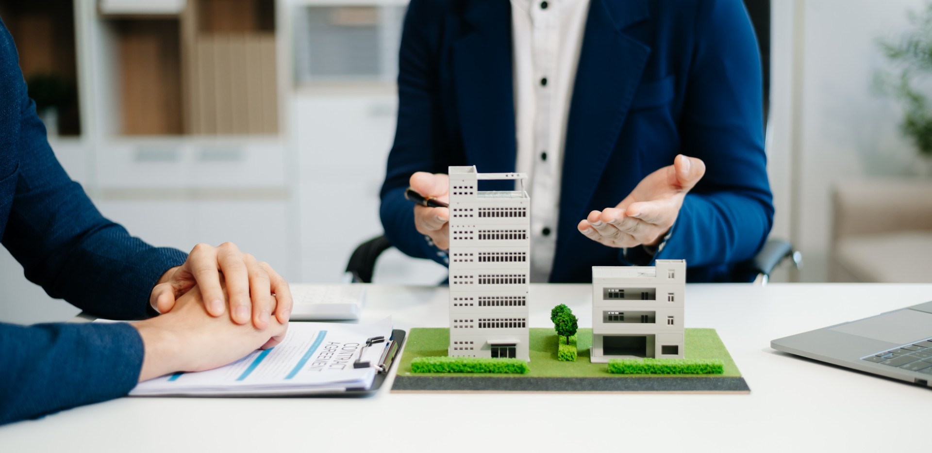 Deux hommes en réunion montrant une maquette d'un immeuble