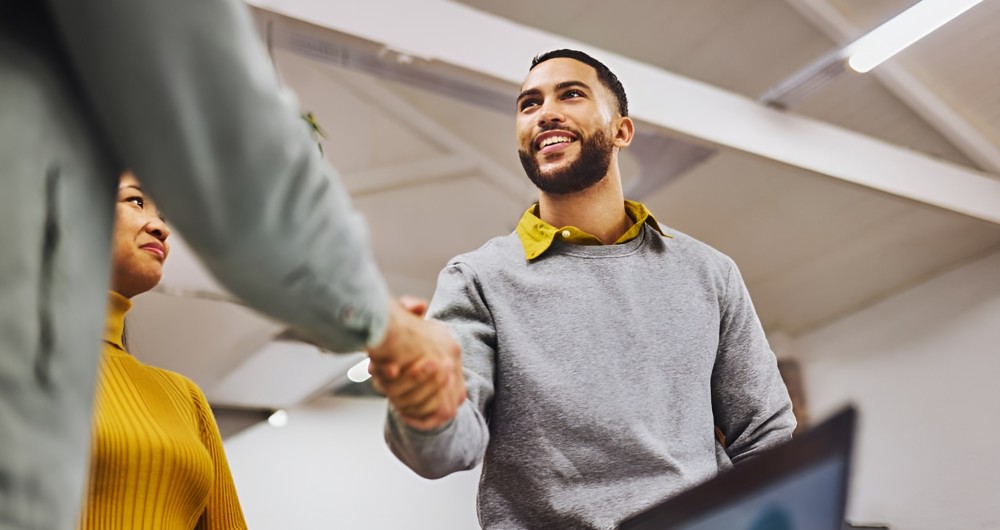 Deux personnes se serrent la main dans un environnement professionnel, suggérant une rencontre ou un accord positif.