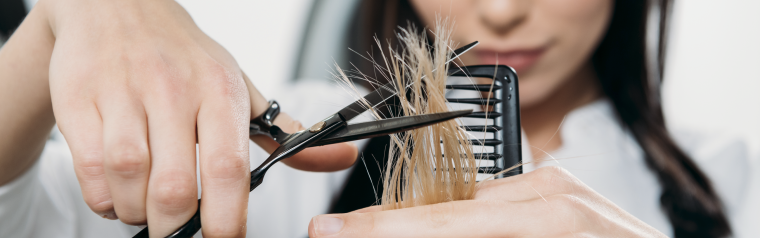 Coiffeuse en train de couper les pointes d'une cliente