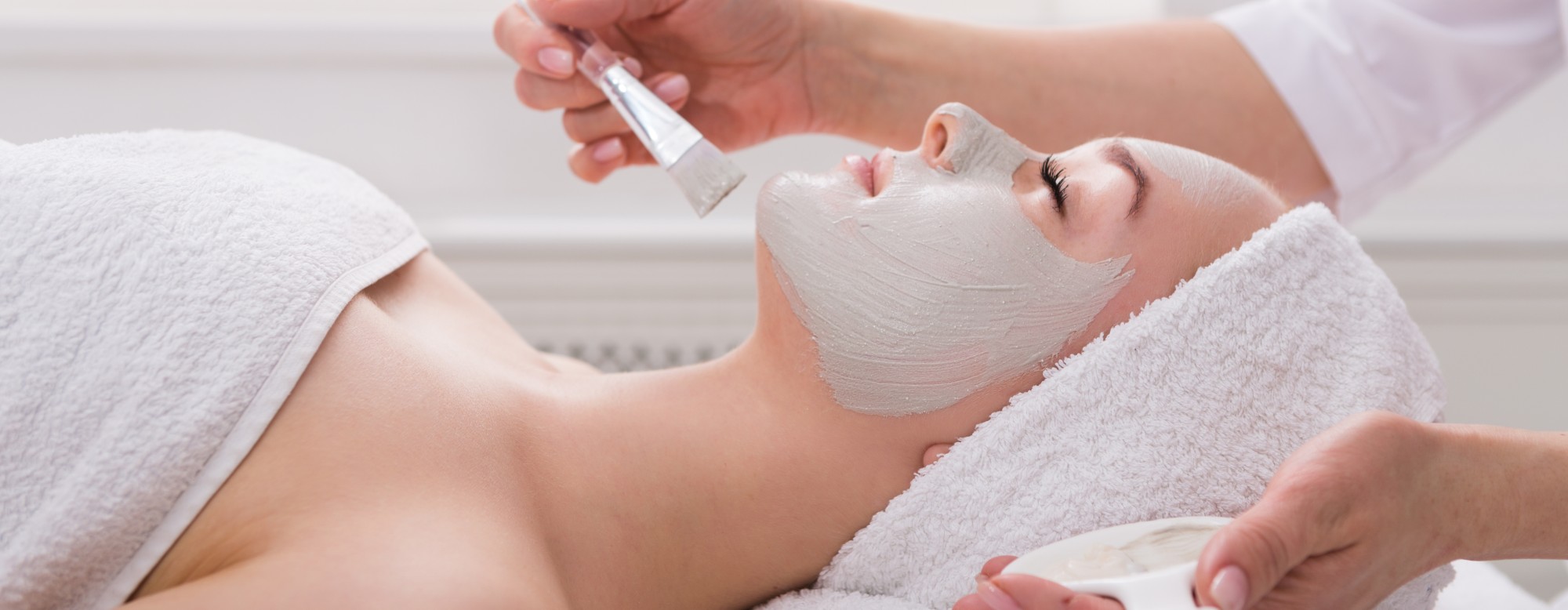 Application d'une crème sur une cliente par une cosméticienne