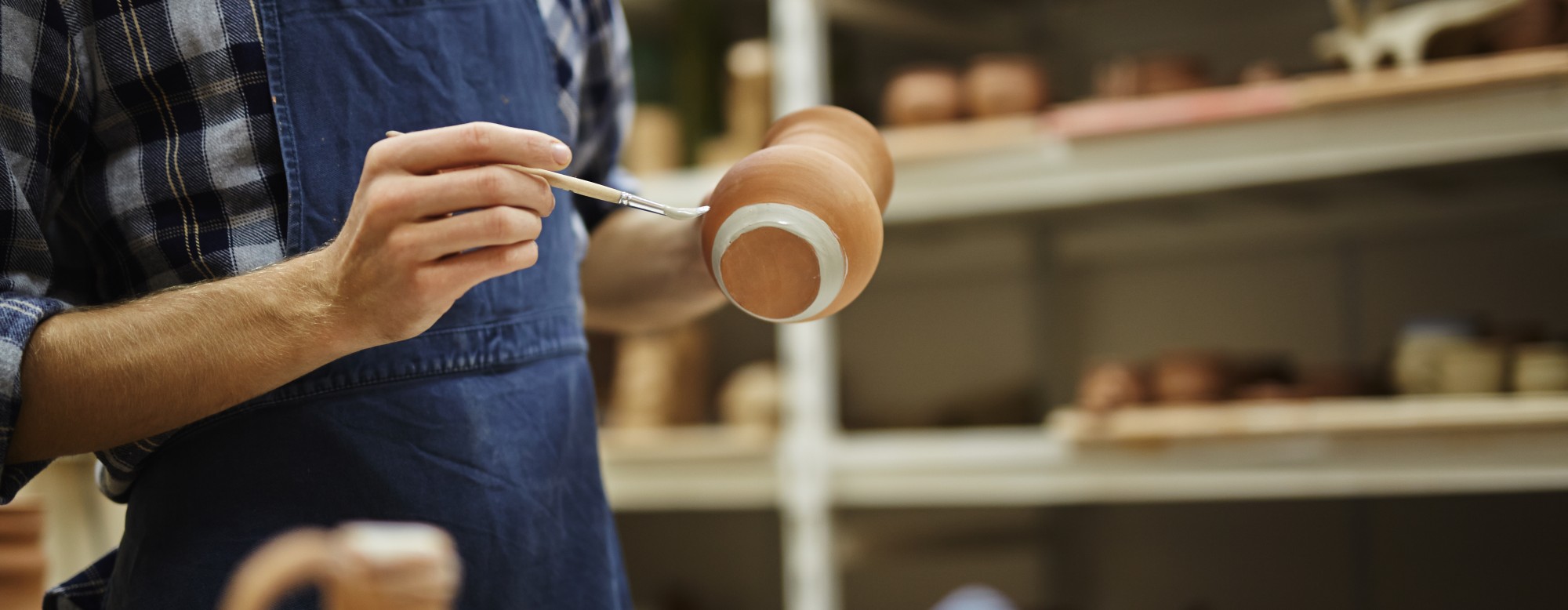 Artisan qui peint une poterie