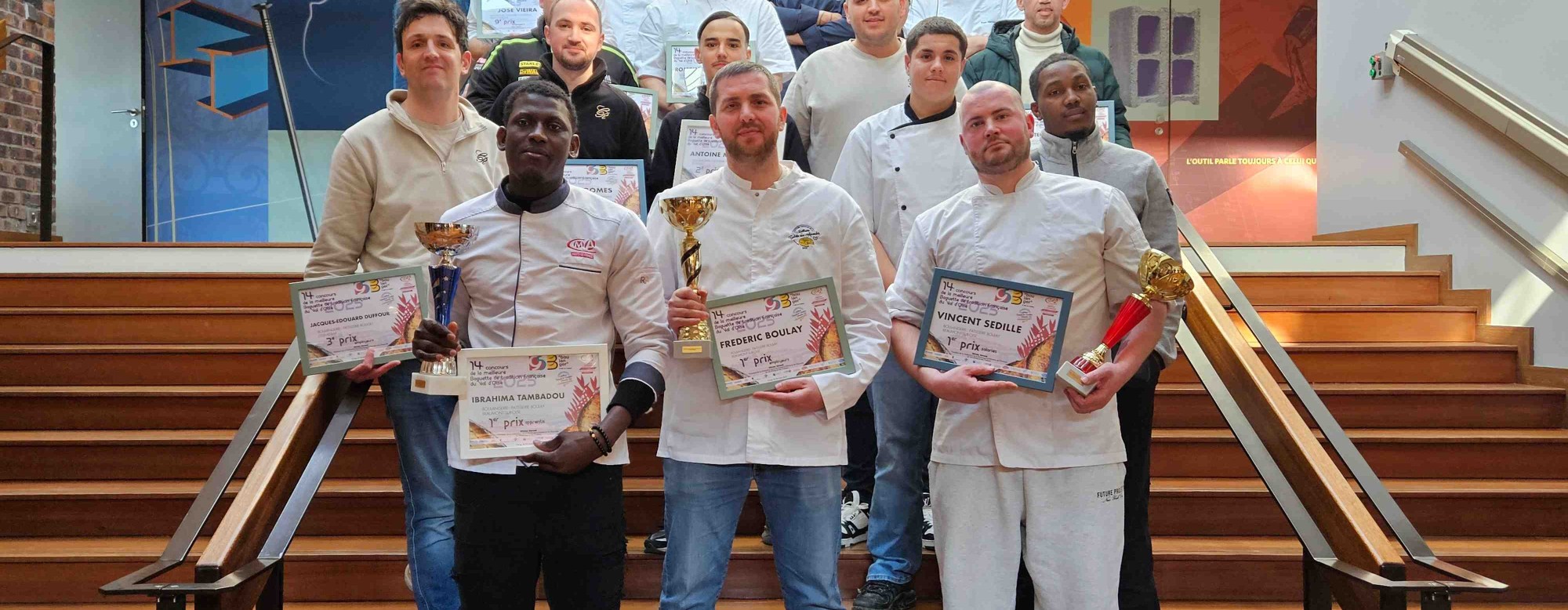 une photo de groupe des gagnants dans des escaliers tenant leurs diplômes et trophées