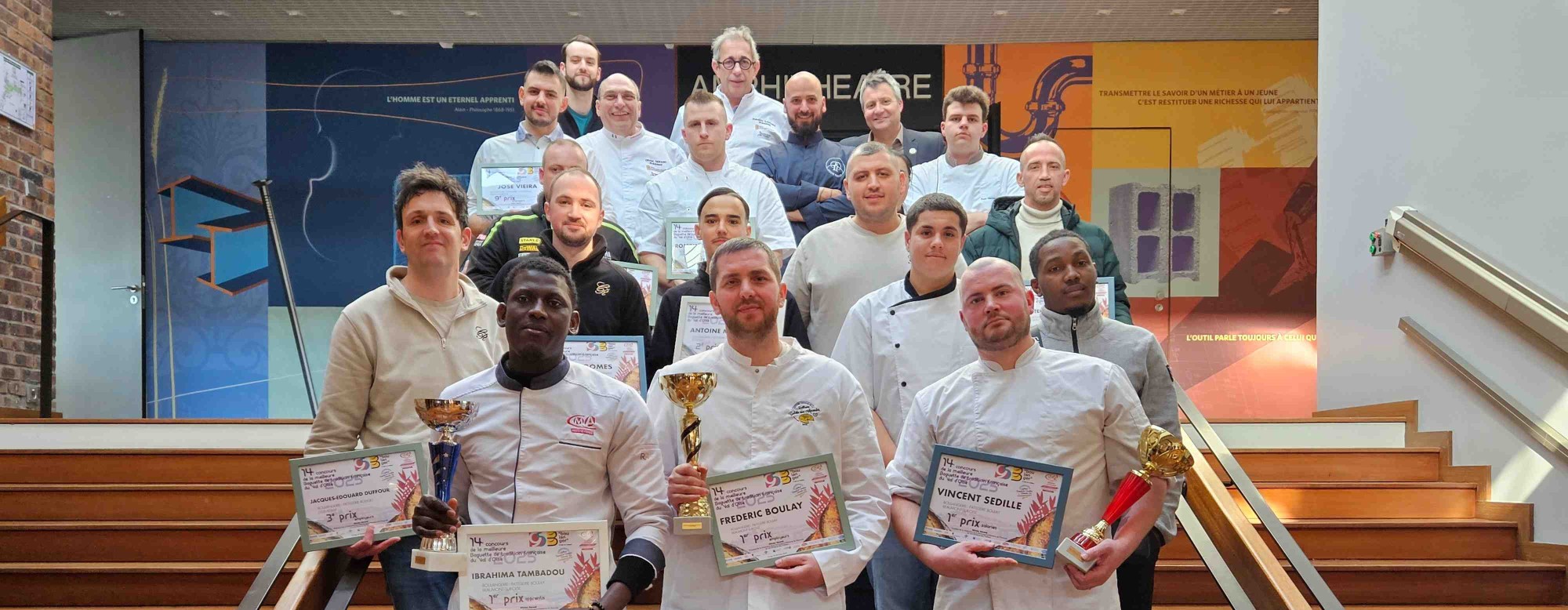 une photo de groupe des gagnants dans des escaliers tenant leurs diplômes et trophées