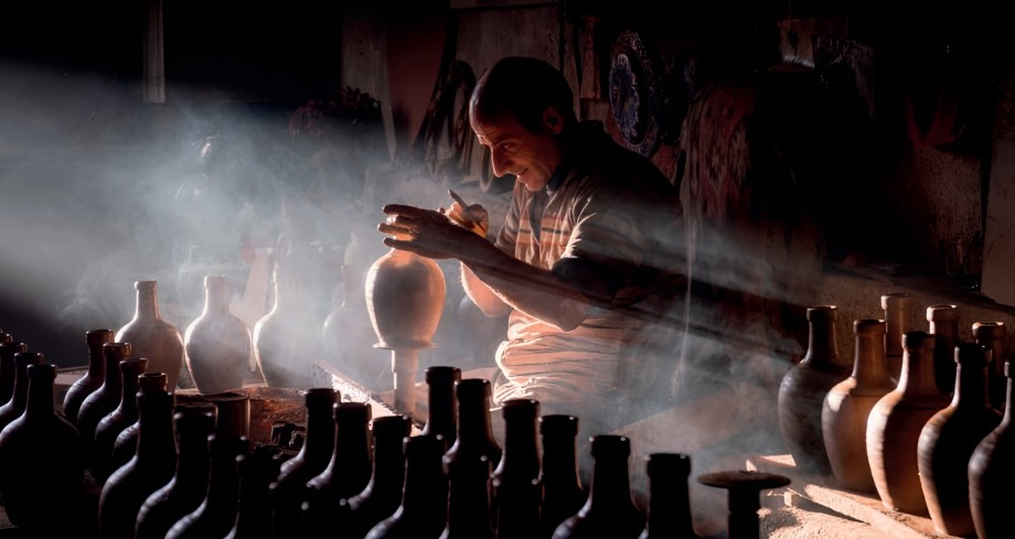 Un potier façonne un vase dans la lumière tamisée de son atelier.