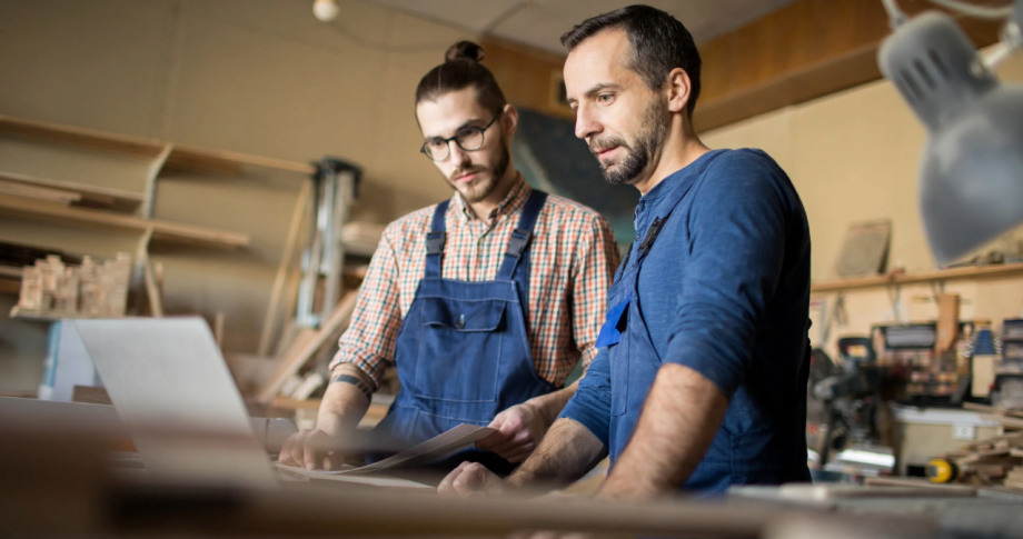 Deux artisans discutent ensemble devant un ordinateur dans leur atelier