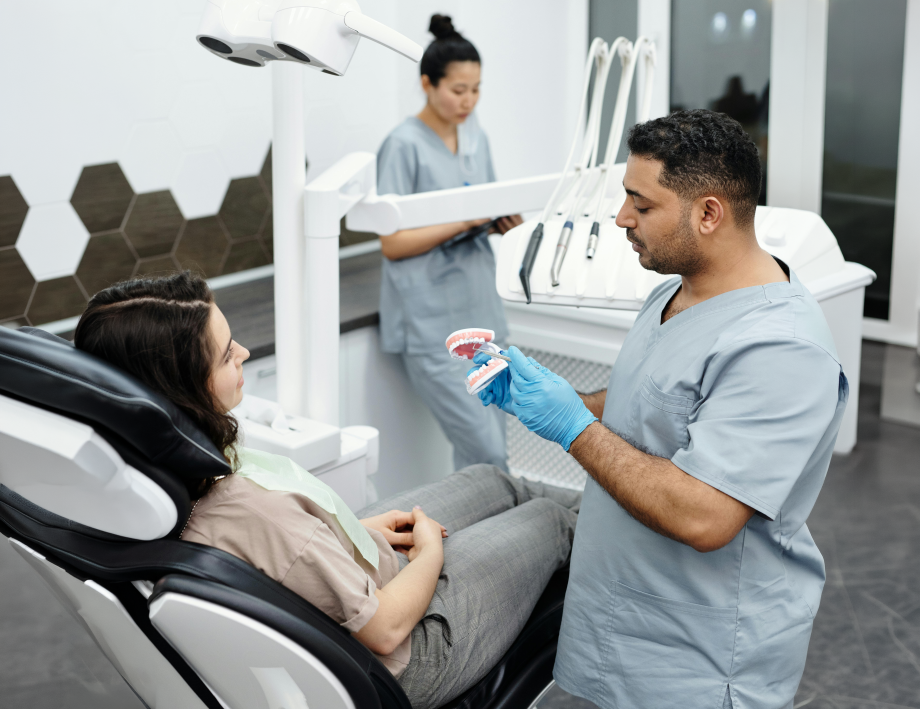 Dentiste expliquant un modèle de mâchoire à une patiente