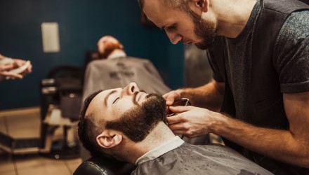 Barbier qui réalise une coupe de barbe dans son salon de coiffure