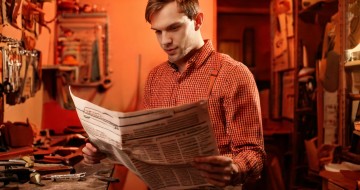 Un jeune artisan qui lit un journal dans son atelier. Cette photo a été générée par l'intelligence artificielle.