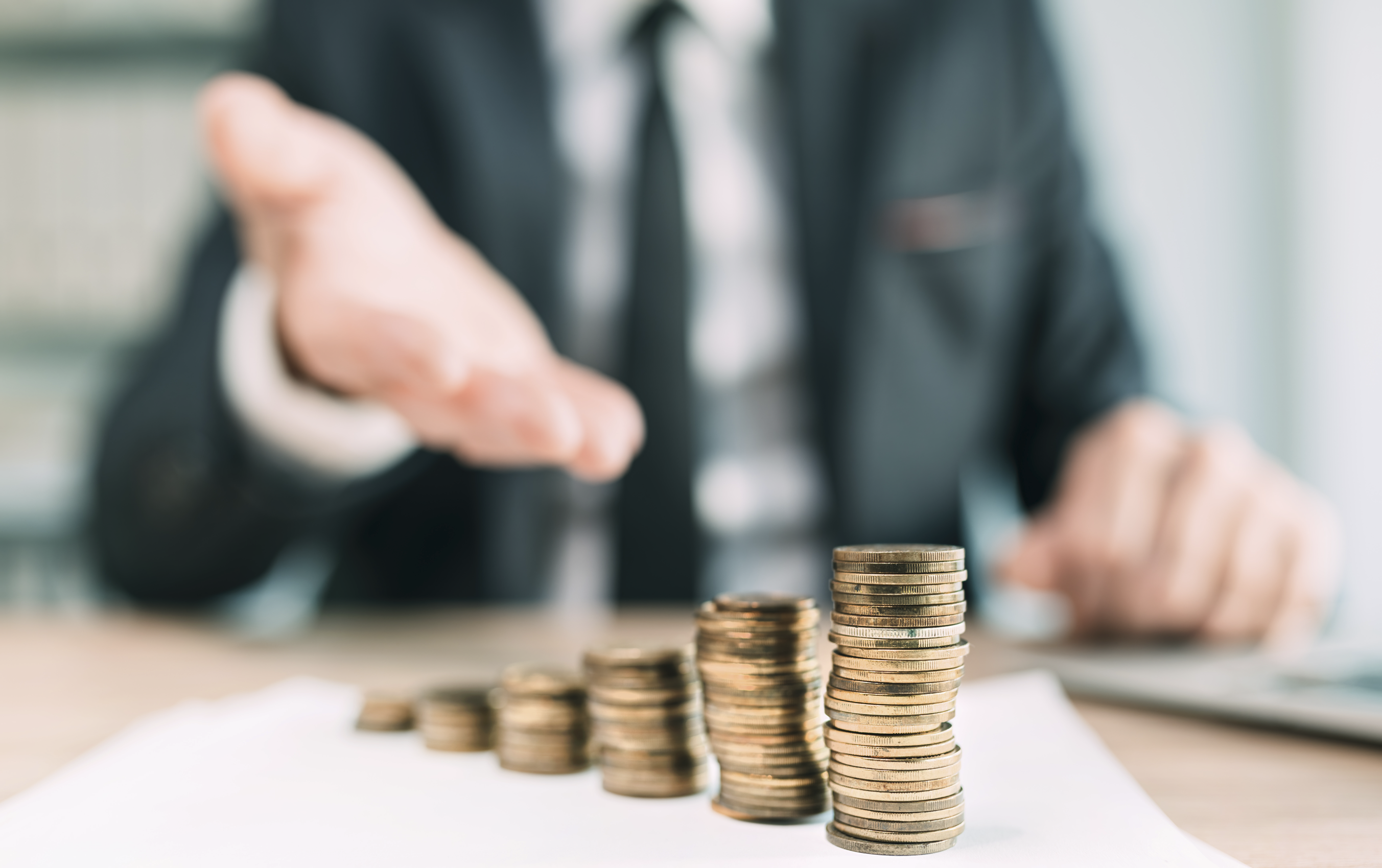 Homme en costume montrant un tas de pièces symbolisant un prêt bancaire